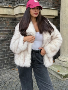 Detail view of plush faux fox fur texture on a warm white winter coat outdoors