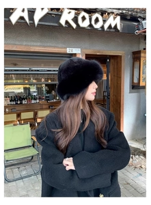 Detailed view of a plush black faux fur bucket hat styled with a warm winter coat