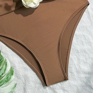 Close-up of brown swimsuit fabric featuring 3D white flower detail and fine stitching