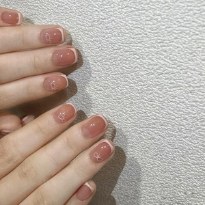 Close-up of rose pink French press-on nails with delicate white bow patterns