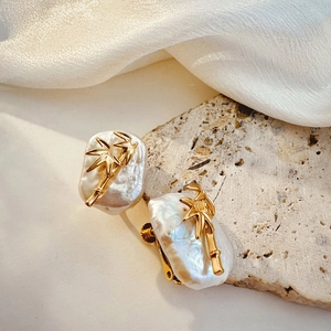 Detail of bamboo-style gold earrings featuring baroque pearls and secure clip-on backings