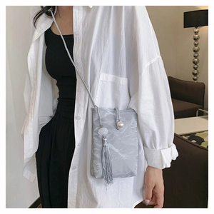 Detail van zilveren geplooide crossbody telefoontas met parelkwast en franjes
