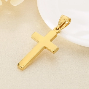 Macro close-up of polished gold cross pendant with high-gloss finish on beige fabric