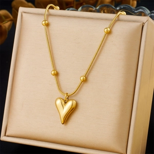 Golden heart pendant necklace with sleek beads on a snake chain shown on a jewelry box