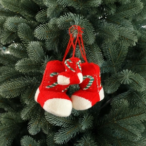 Three red knitted Christmas stocking ornaments hanging on a festive green pine tree branch