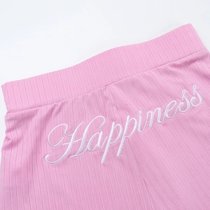 Detail of pink ribbed knit fabric with white Happiness embroidery on elastic waistband
