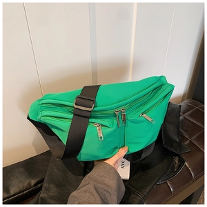 Detail of bright green nylon crossbody bag showing silver zippers and wide black strap