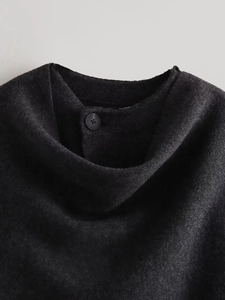 Detailed close-up of the black knit neck area with a simple round button on fabric