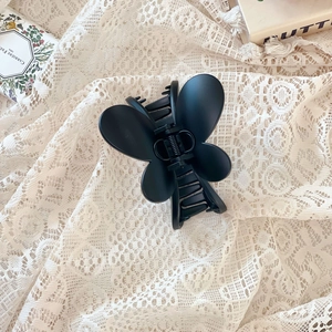 Détail de la pince à cheveux papillon noir mat avec ressort en métal sur dentelle
