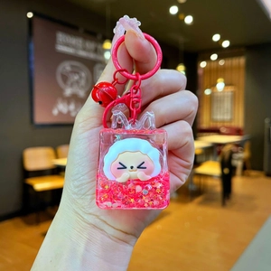 Detail of red liquid shaker keychain with white sheep figure, stars, and small bell