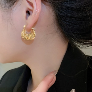 Detailed view of vintage gold hollowed floral earring on model with elegant French style