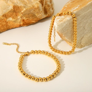 Detailed view of 18K gold-plated beaded bracelets on natural stone, chic minimal style
