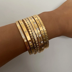 Vintage gold bangle set with star engravings and zircon stones worn on a wrist