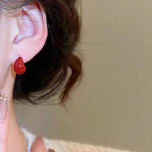 Close-up of red teardrop earrings on model for a retro minimalist fashion look