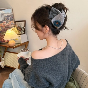 Pince à cheveux noeud tricoté gris avec fleur bleue portée en salon chic