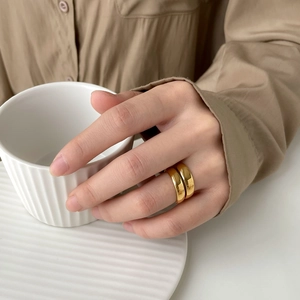 Close-up of a double-layered wide golden ring set with a high-polished metallic finish