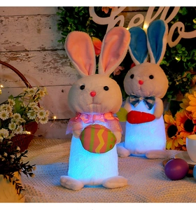Close-up of two glowing plush Easter bunnies with carrot and colorful egg on wood background