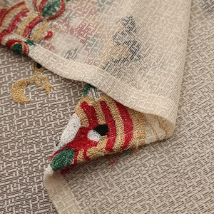 Macro shot of festive Christmas embroidery with stockings and stars on beige lace fabric