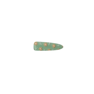 Cute light green acrylic hair clip with orange floral pattern on a clean white background