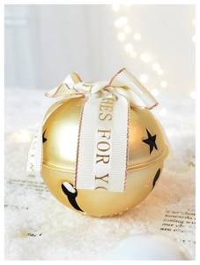 Detailed close-up of golden hollow bell ornament with elegant white Swanlace ribbon and stars