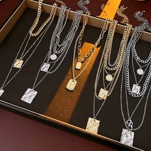 Layered gold and silver necklace with hammered metal pendants on jewelry display