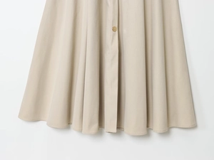 Détail de la robe beige élégante avec boutons dorés et texture de tissu plissé lisse