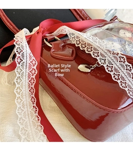 Detailed macro view of glossy red patent leather ita bag with silk bows and lace trim