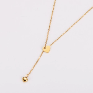 Detail einer goldenen Herz-Quasten-Halskette mit Y-Ketten-Design und polierter Metalloberfläche
