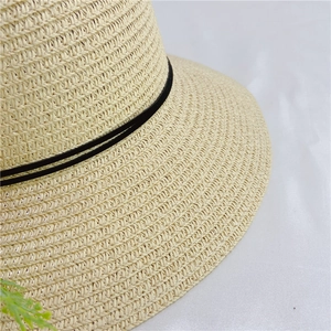 Close-up of beige woven straw hat detailing the fine texture and black ribbon trim