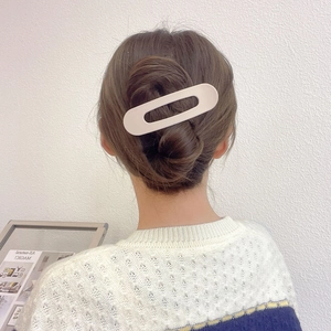 Rear view of model wearing a large cream oval hollow hair clip for elegant styling