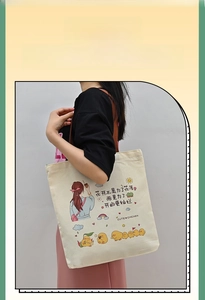 Close-up of cream canvas tote bag with artistic cartoon illustrations and motivational text