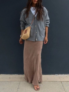 Full-length view of a gray knit cardigan paired with a brown maxi skirt and woven straw bag
