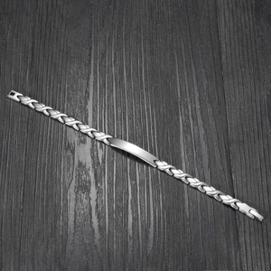 Polished silver stainless steel bracelet with a blank identity plate on dark wood