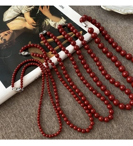 Détail artistique de colliers de perles rouges avec fermoirs argentés sur un livre d'art