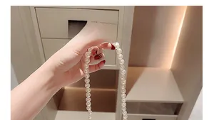 Detailansicht einer handgehaltenen cremeweißen Perlenkette mit glatten runden Perlen