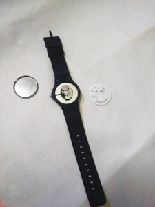 Disassembled view showing inner quartz movement, black silicone strap, and metal back case