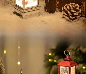 Close-up of decorative Christmas lanterns with glitter snow and warm LED lighting inside