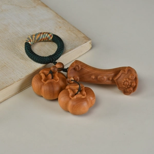 Detail of hand-carved persimmon and ruyi wooden pendants with a green woven ring