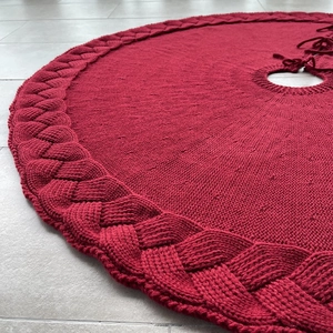 Close-up of red knit Christmas tree skirt with thick braided border and soft texture