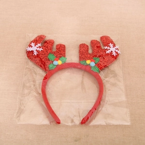 Detail of Christmas reindeer antler headband with sequins and holly in clear packaging