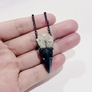 Detailed close-up of dark gothic bird skull pendant necklace with matte black beak