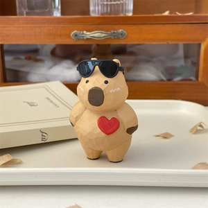 Détail d'une figurine de capybara en bois avec lunettes noires et un cœur rouge