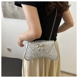 Silver sequin shoulder bag with chain strap and metallic bow detail shown on model