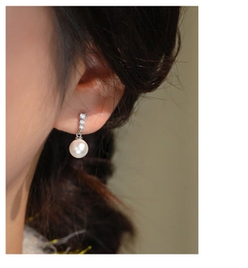 Close-up of pearl drop earring with three small zircons on silver s925 stud