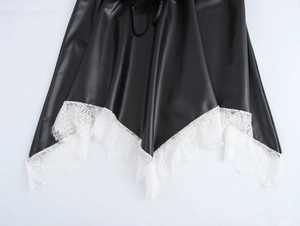 Détail d'une robe en similicuir noir avec dentelle blanche et ourlet irrégulier chic