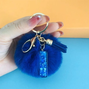 Blue faux fur pompom keychain with matching tassel and gold hardware detail