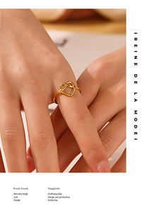 Primo piano dell'anello a cuore placcato oro 18K su dito con illuminazione calda