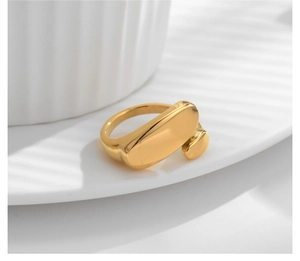 Detailed view of a gold plated irregular geometric oval open ring on a white plate