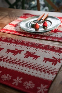 Close-up of red and beige jacquard placemats with woven reindeer and snowflake patterns