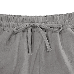 Detail of grey linen trousers showing elastic drawstring waist and woven fabric texture